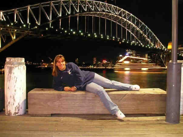 a woman laying on a bench with a bridge in the background