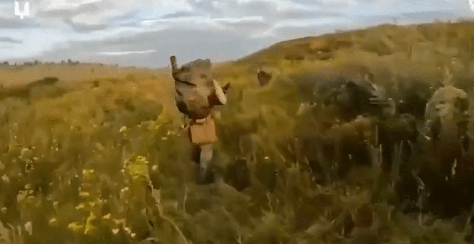 Ukrainian soldiers walk through a field in their secret attack