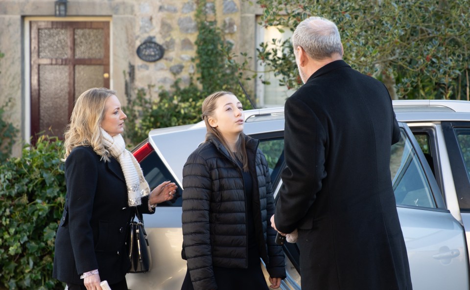 a woman in a black jacket is talking to a man in a black coat