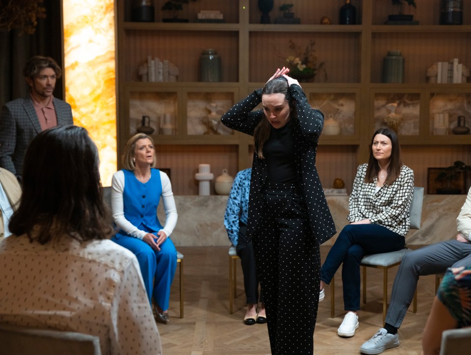 a woman in a black polka dot suit stands in front of a group of people