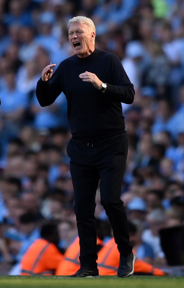 a man in a black sweater and black pants stands on a field