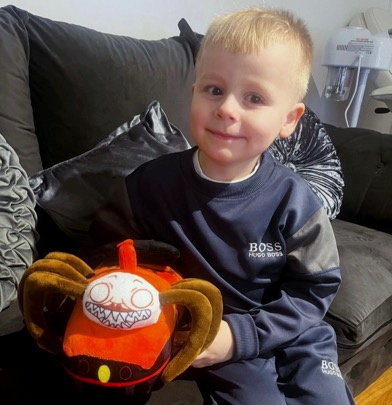 a young boy is sitting on a couch holding a stuffed animal .