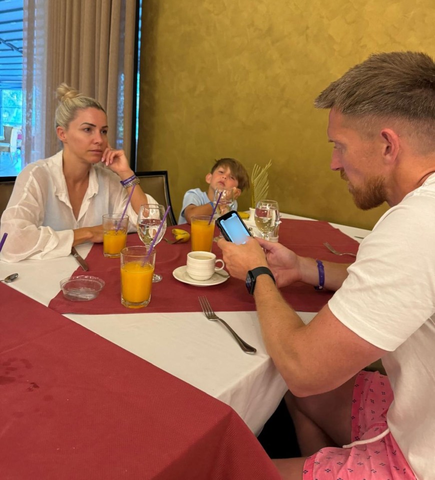 a man is looking at his phone while sitting at a table with his family