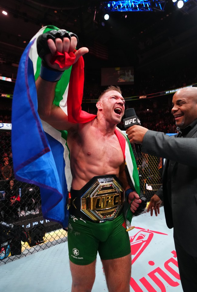 a man wearing a ufc belt holds up a flag