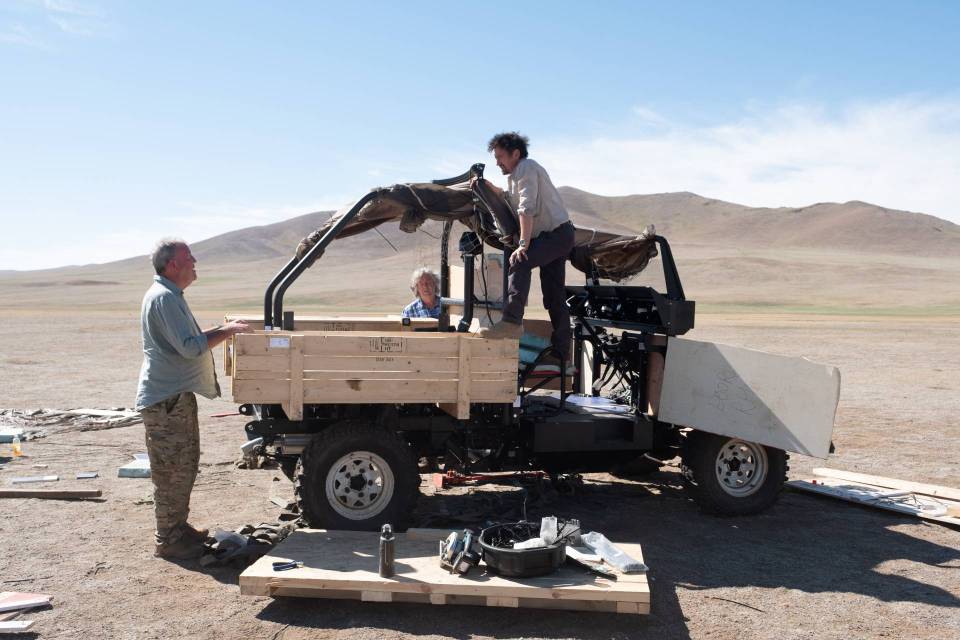 three men are working on a vehicle that has a box on the back that says ' u.s. army ' on it