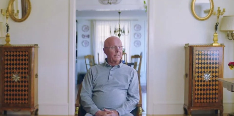 a man sits in a chair in a living room with a sign that says prime