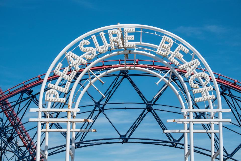 a roller coaster is behind a sign that says pleasure beach