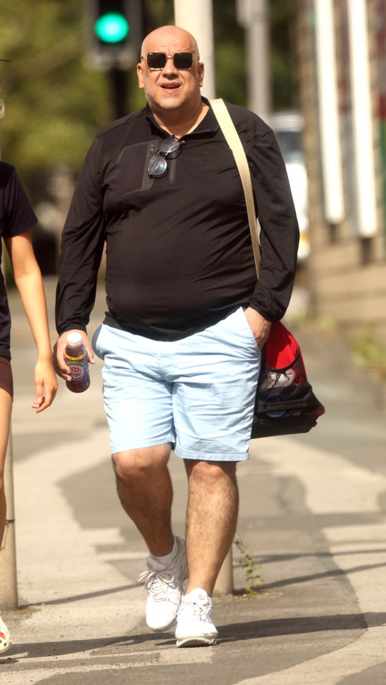 a man wearing shorts and a black shirt is walking down the street