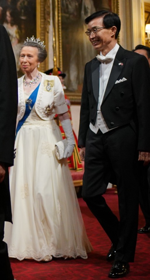 a woman in a white dress is walking with a man in a tuxedo