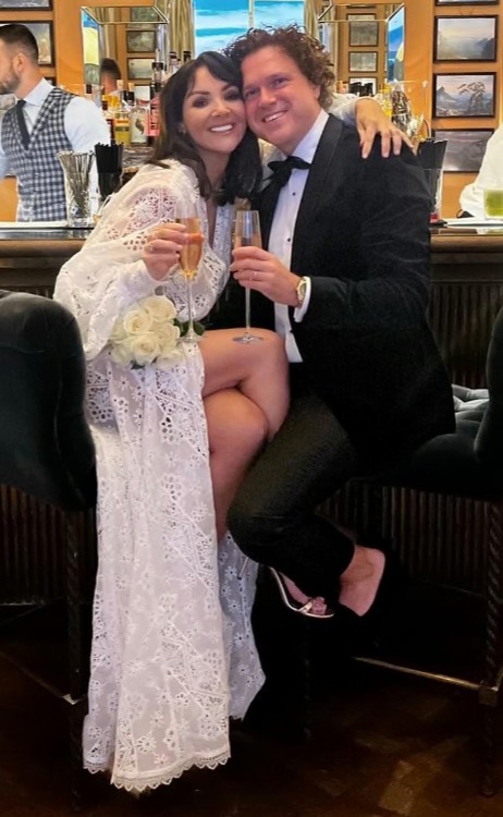 a bride and groom sitting at a bar holding champagne glasses