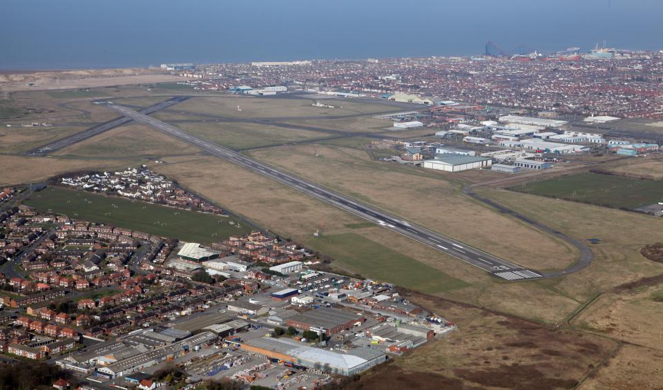 an aerial view of a runway with a city in the background