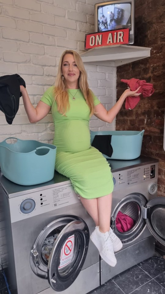 a woman in a green dress sits on a washing machine under a sign that says on air