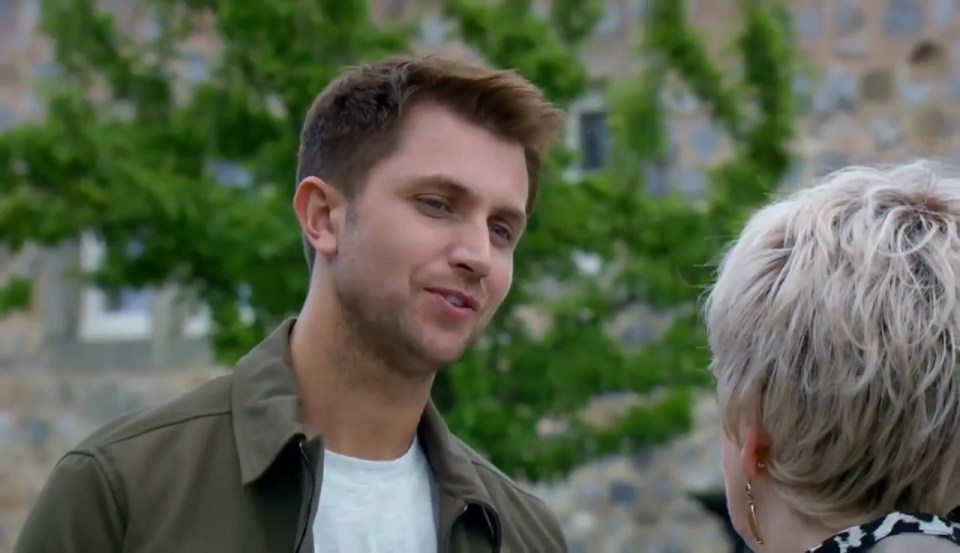 a man in a green jacket is talking to a woman in a white shirt .