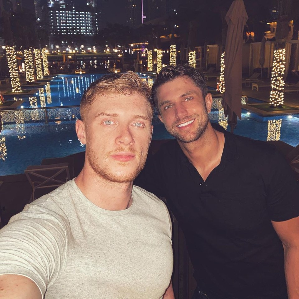 two men are posing for a picture in front of a swimming pool