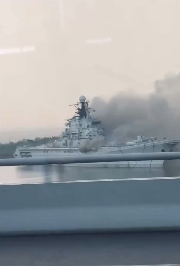 a large military ship with smoke coming out of it .