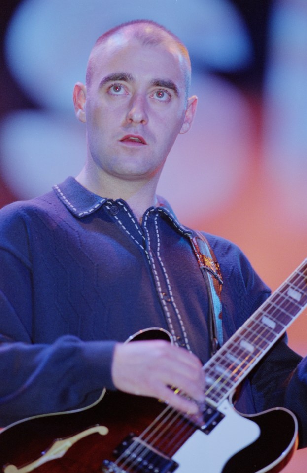 a bald man playing an epiphone guitar on stage