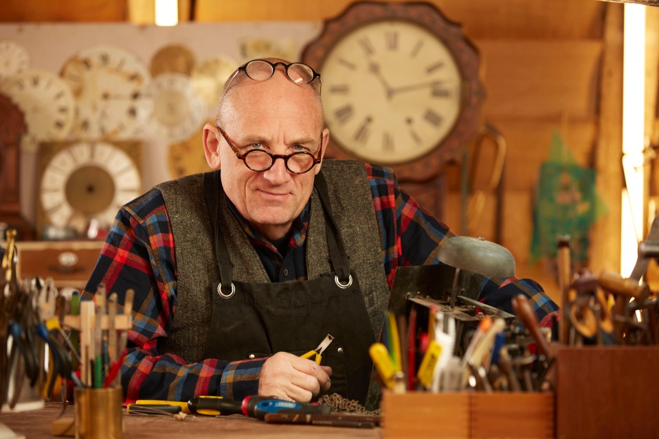 a man wearing glasses and an apron is working on a clock