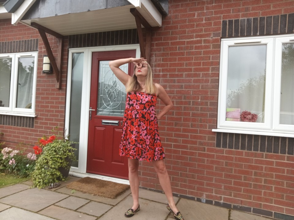 a woman in a red dress stands in front of a red door