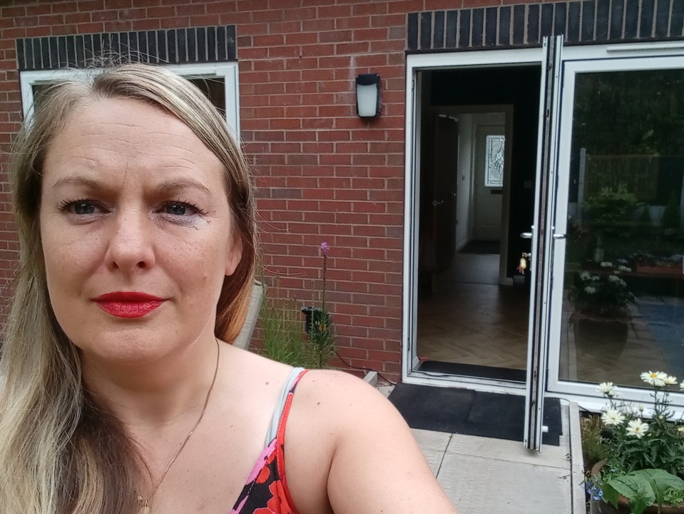 a woman with red lipstick stands in front of a brick house