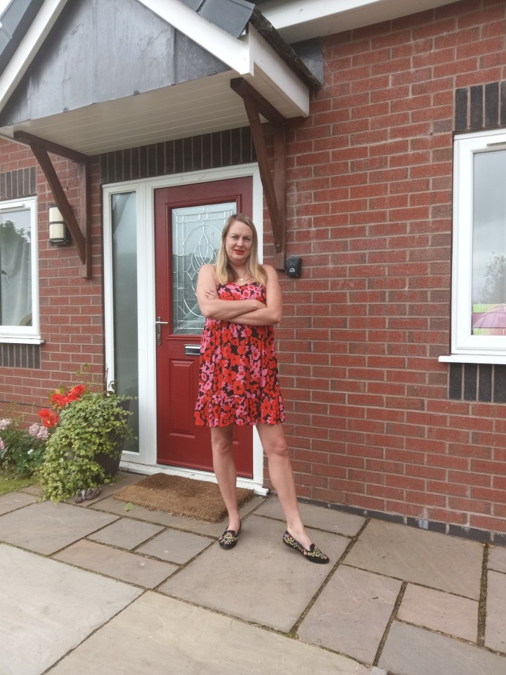 a woman in a red dress stands in front of a red door