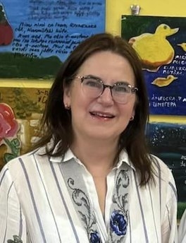 a woman wearing glasses and a striped shirt is smiling in front of a painting of a duck .