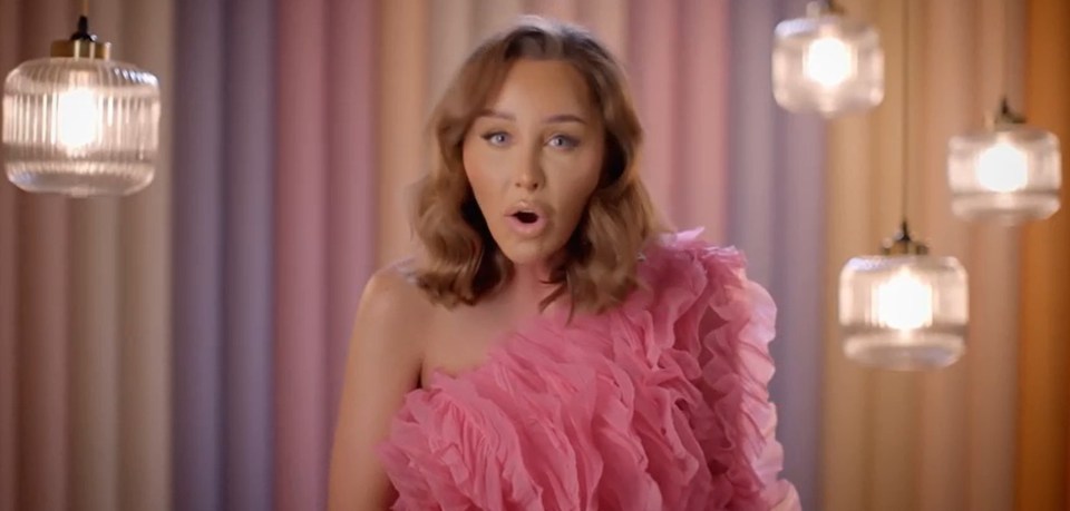 a woman in a pink dress is standing in front of a rainbow curtain .