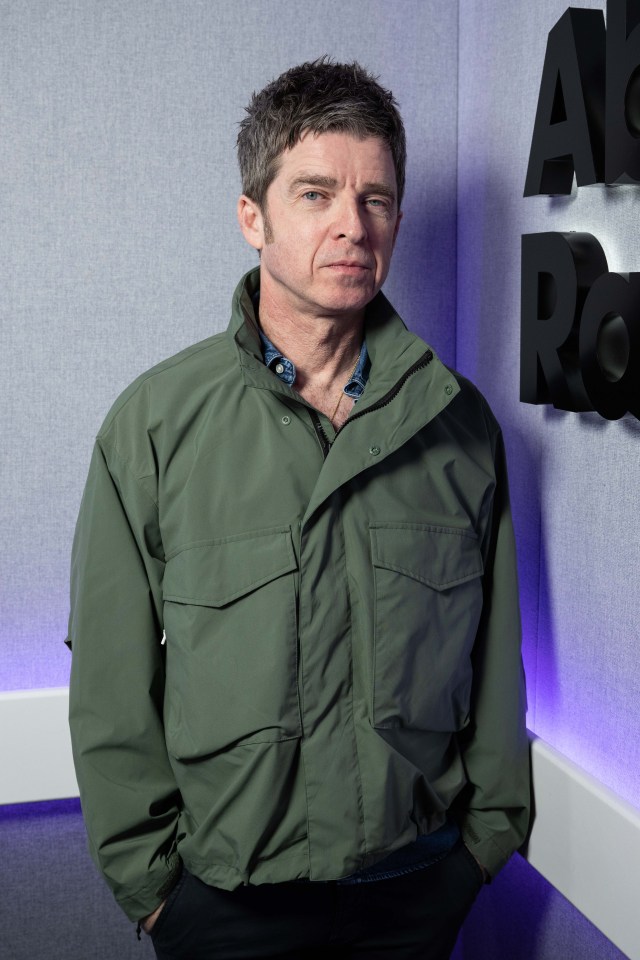 a man in a green jacket stands in front of a wall with letters a and r on it