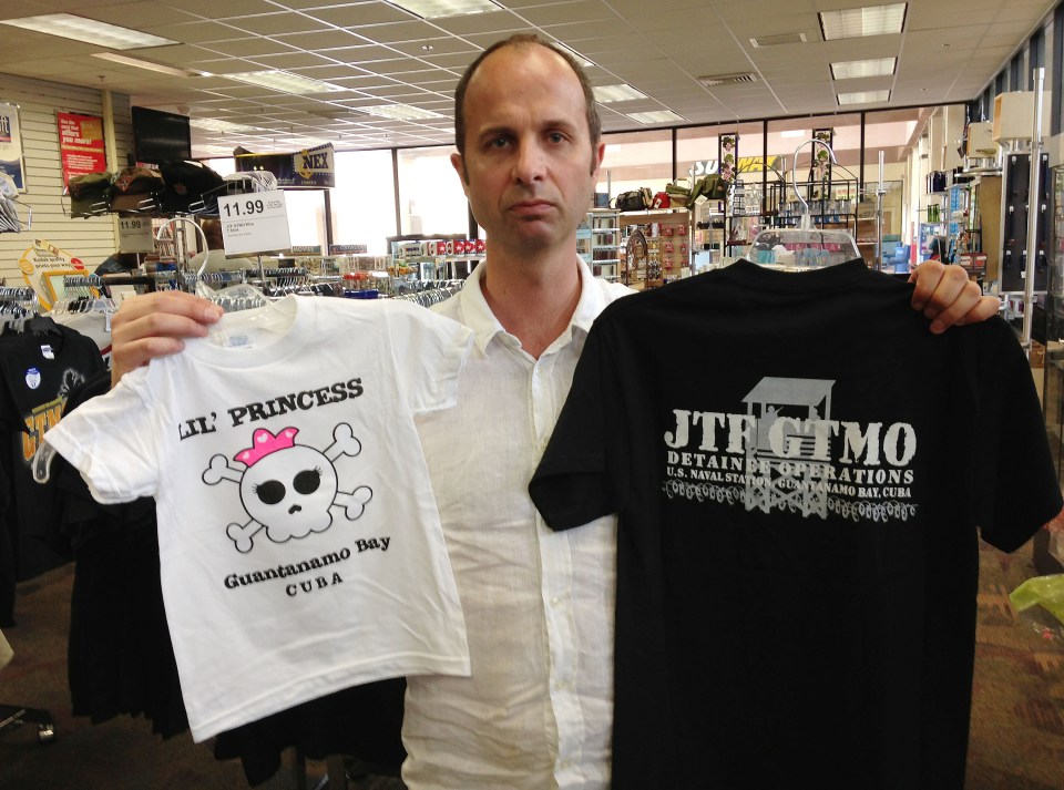 Sun man Oliver holds souvenir t-shirts at the tat-filled gift shop