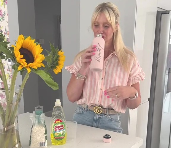 a woman drinking from a pink bottle that says honey