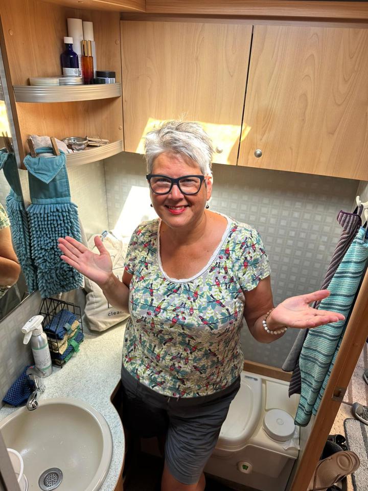 a woman wearing glasses stands in a bathroom next to a sink