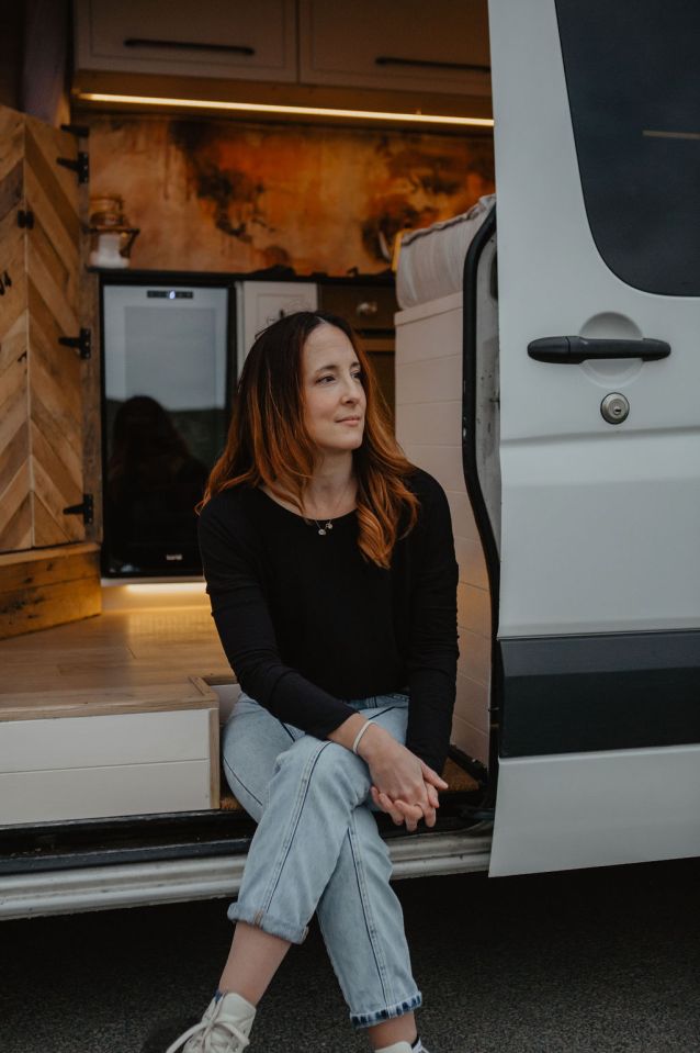 a woman sits in the doorway of a white van