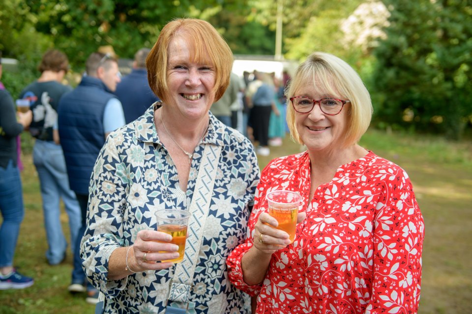 two women are holding up glasses of beer and smiling