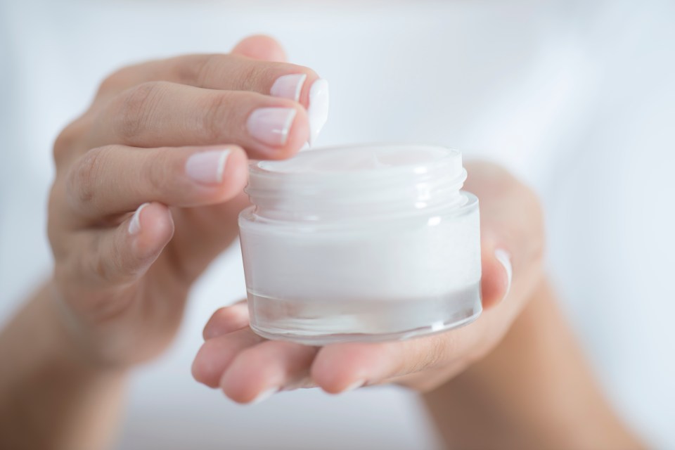 a woman is holding a jar of cream in her hands