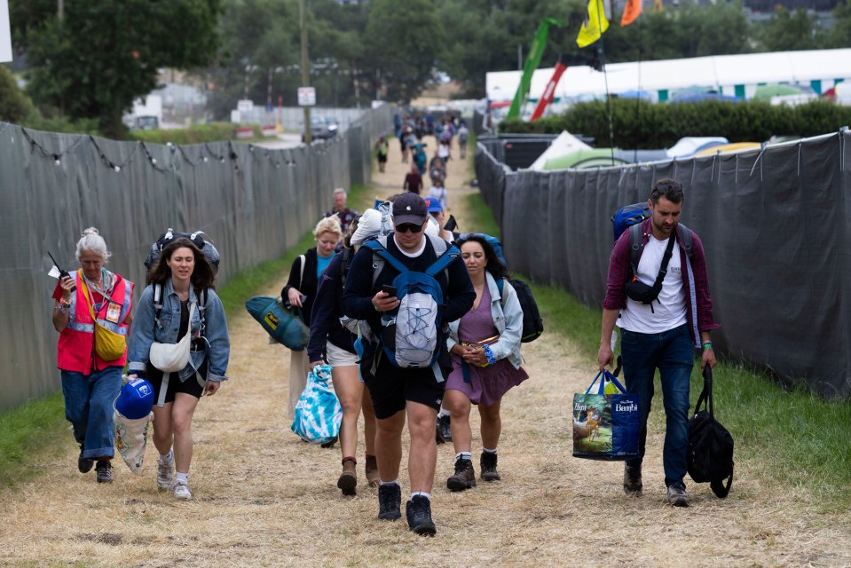 a group of people walking down a dirt path carrying a bag that says homer 's