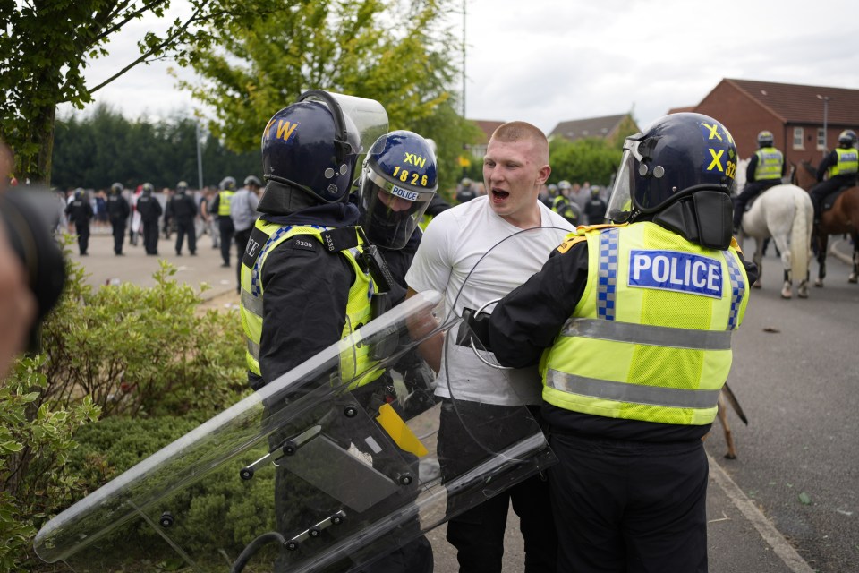 Police officers detaining a man now identified as Liam Grey, 20, during the riot outside a migrant hotel in Rotherham