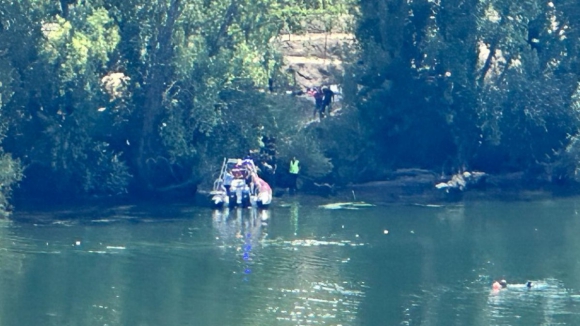 a group of people are standing on a shore next to a body of water