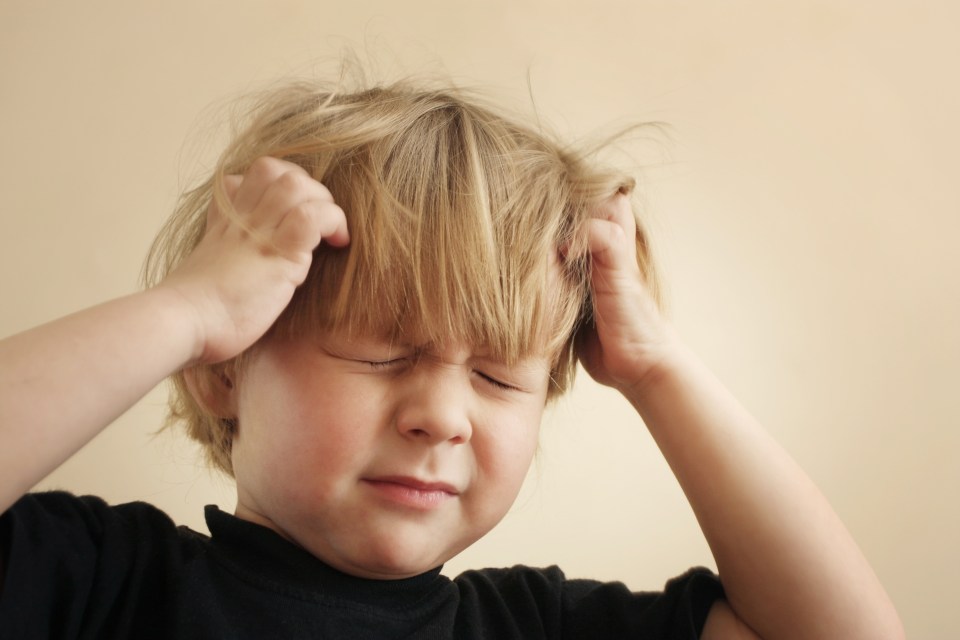 a young boy has his eyes closed and his hands on his head