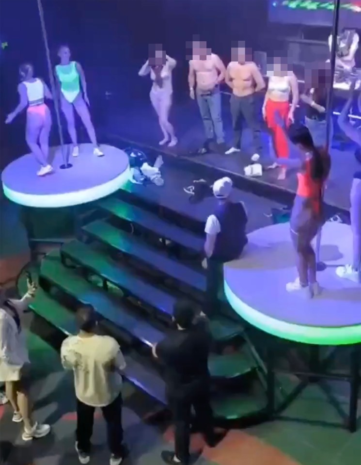 a group of people are dancing on a stage in a club