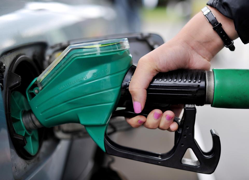 a woman with pink nails is pumping gas into a car