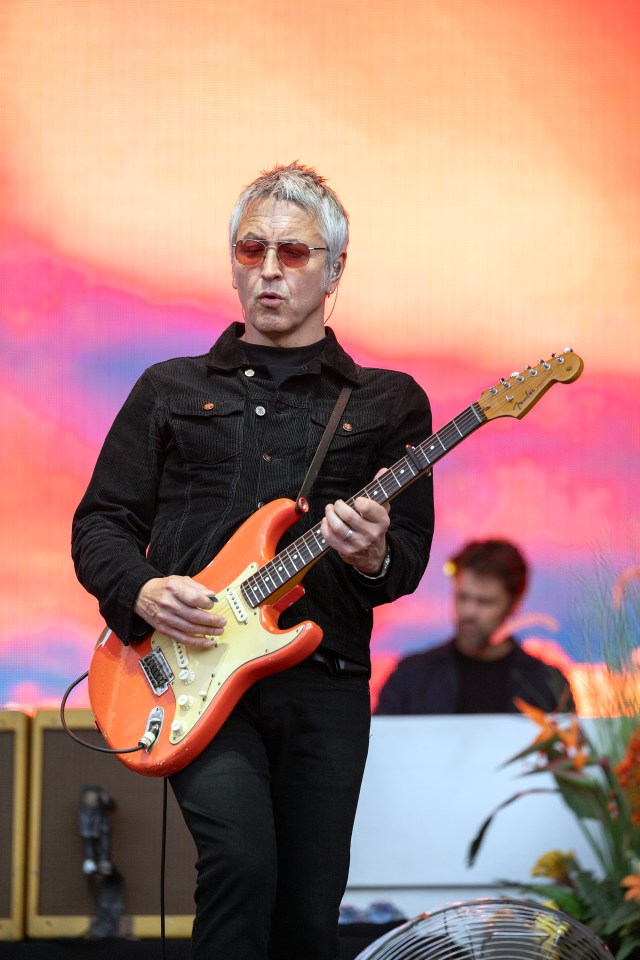 a man in a black jacket is playing an orange guitar