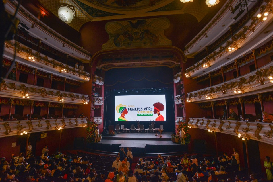 a large auditorium with a screen that says mujeres afri on it