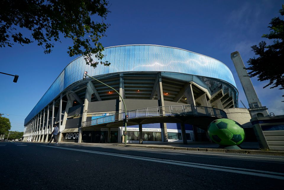 a soccer ball sits on the sidewalk in front of a stadium