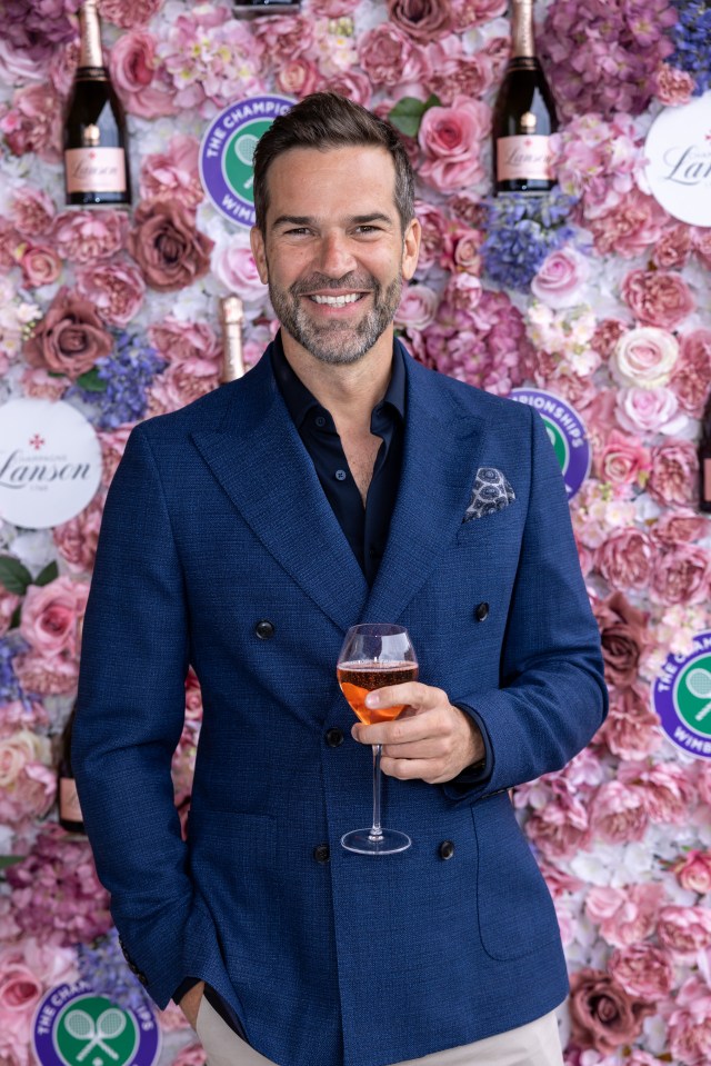 a man in a blue suit is holding a glass of wine