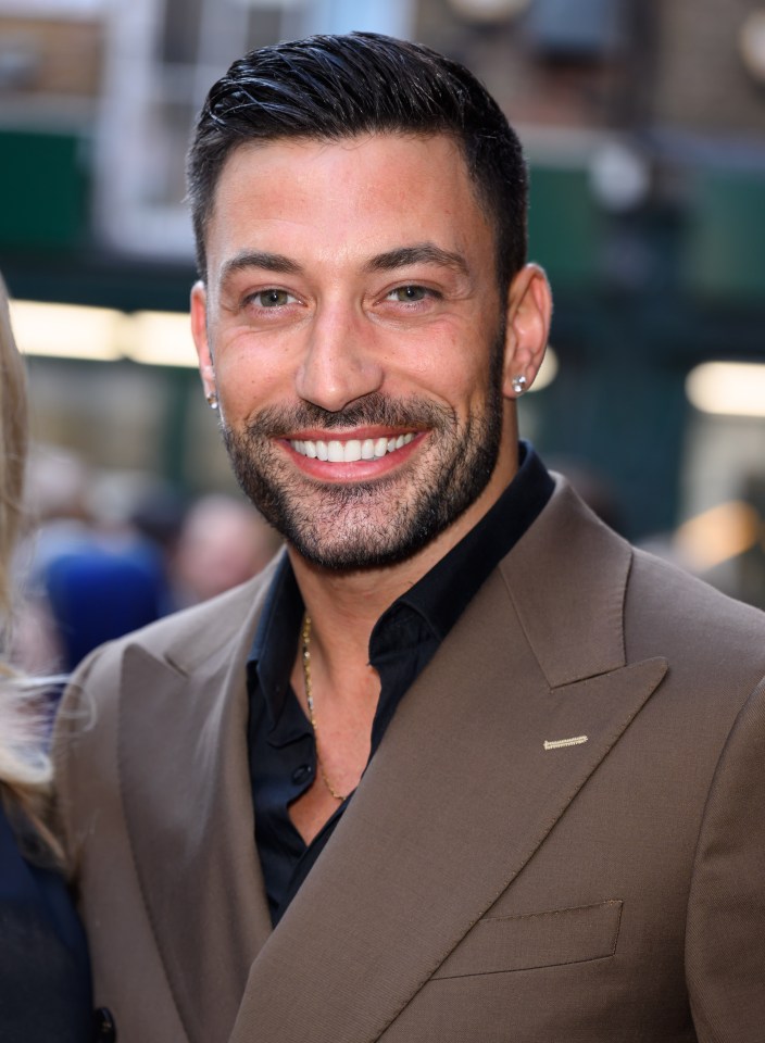 a man with a beard and earrings smiles for the camera