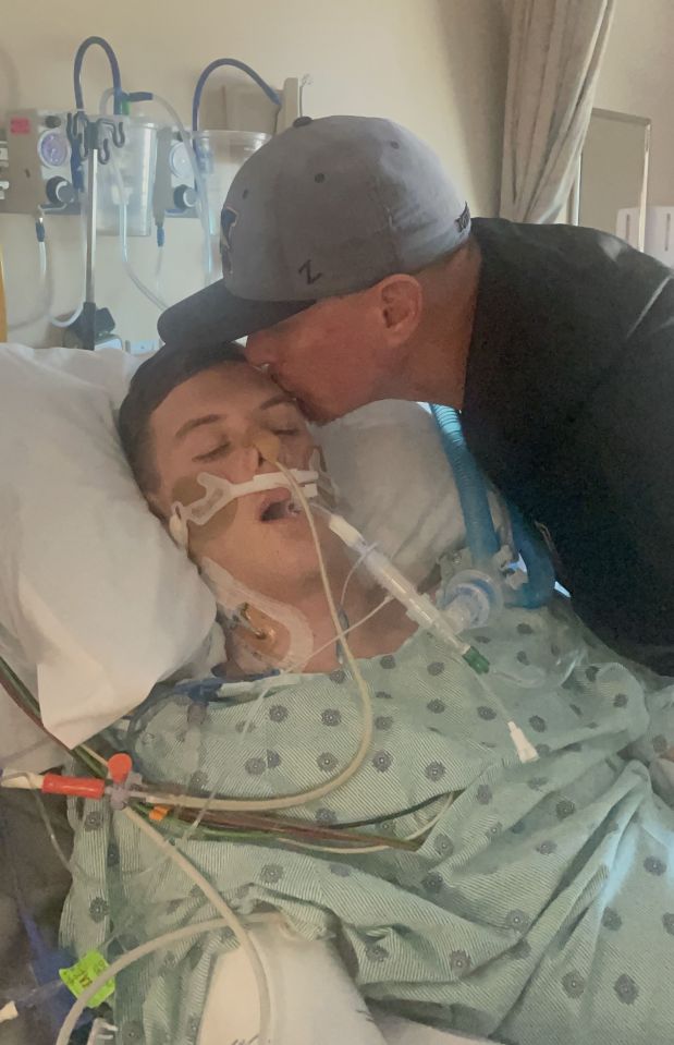 a man in a z hat kisses a boy in a hospital bed