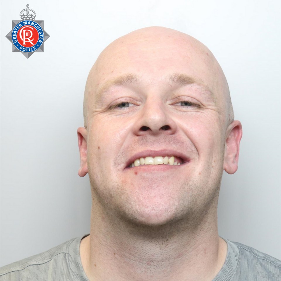 a man is smiling with a greater manchester police logo behind him