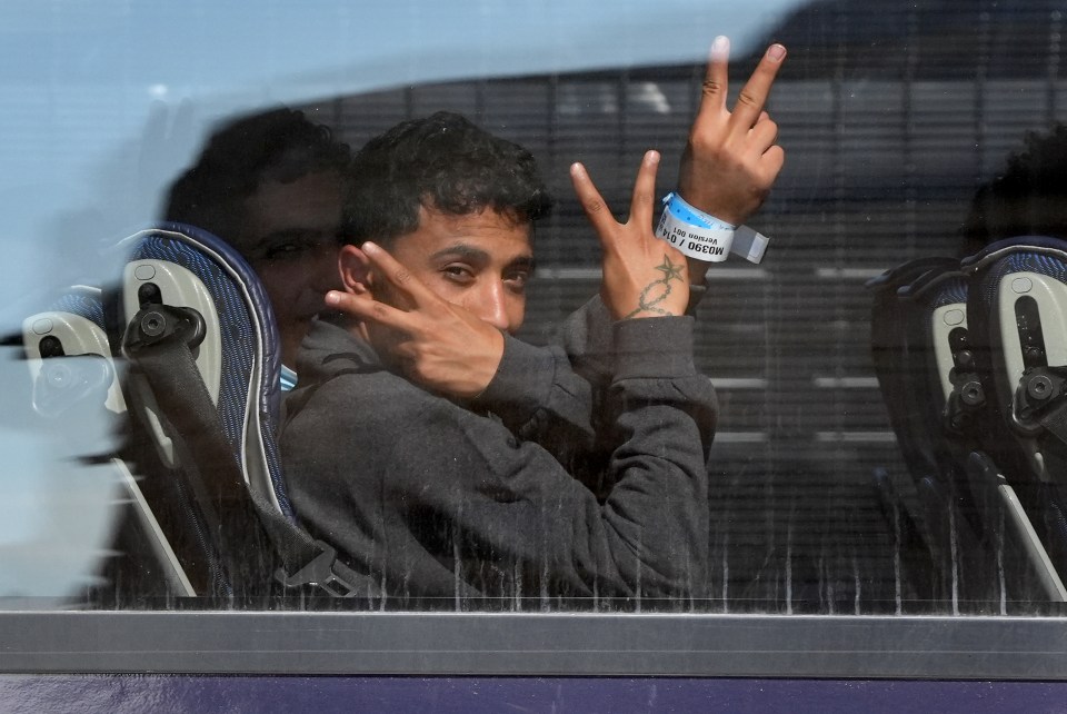 Jubilant migrants are driven away from the Border Force compound after arriving from France