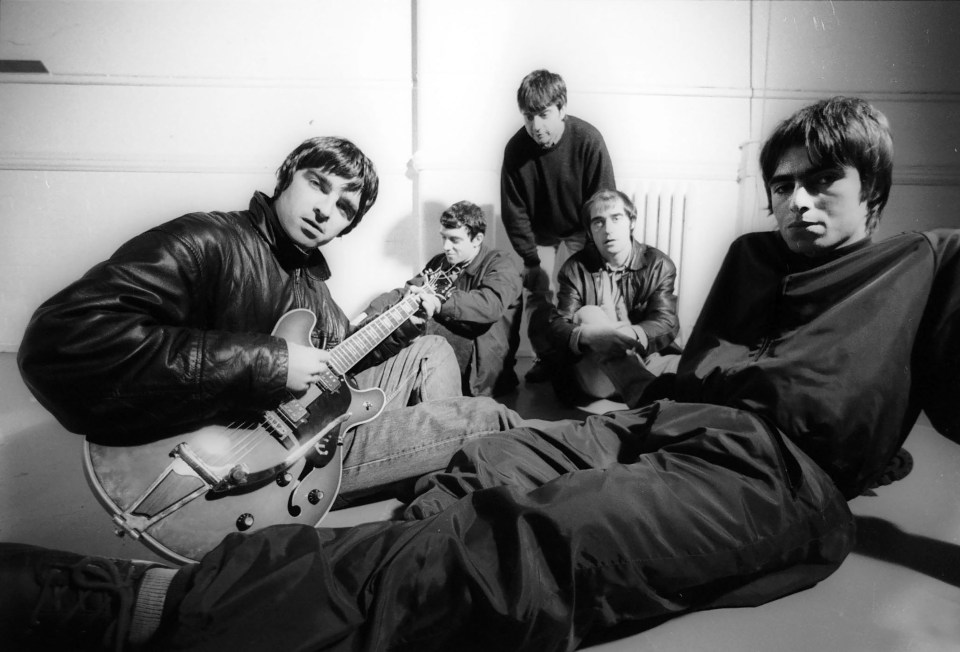 a black and white photo of a group of men with one man playing a guitar