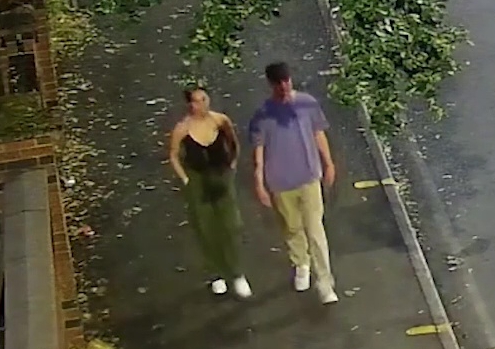 a man and a woman are walking down a sidewalk .