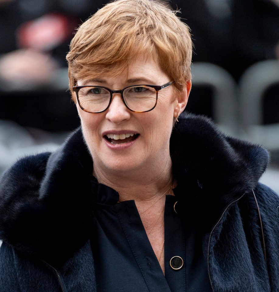 a woman wearing glasses and a fur coat smiles